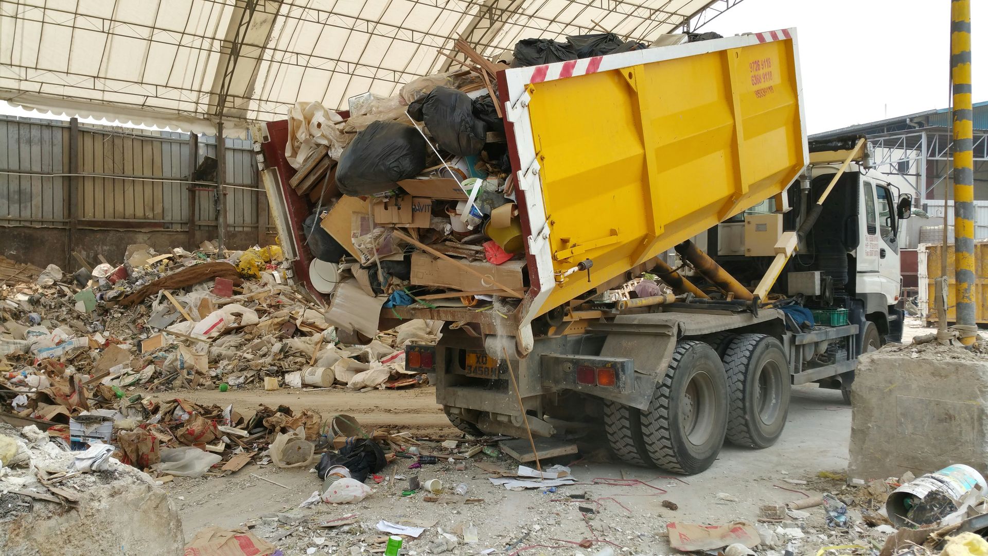 A yellow truck dumping trash at a facility